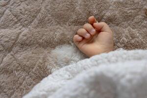 un Derecha mano de dormido asiático bebé en el alfombra foto