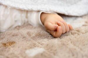 un Derecha mano de dormido asiático bebé en el alfombra foto