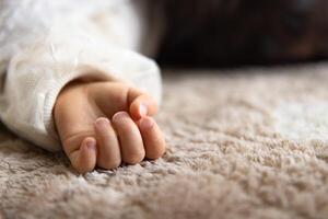 un izquierda mano de dormido asiático bebé en el alfombra foto