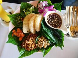 A Thai dish called Miang Kham consists of betel leaves, ginger, dried shrimp, lime, shallots, chilies, mixed together and topped with a sweet dipping sauce photo