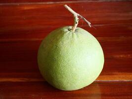 Green grapefruit is put on a brown wooden table photo