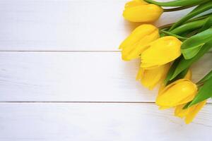 Spring composition with bouquet of yellow tulips on a white wooden background. Close-up. Copy space. Top view. Flatlay. Selective focus. photo