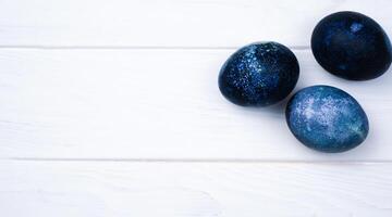 Easter eggs painted with natural dye in blue on the white wooden background. Banner. Close-up. Top view. Place for text. photo