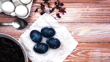 Easter eggs painted with natural dye in blue on the table. The process of dyeing eggs with natural food coloring at home. Close-up. Top view. Copy space. photo