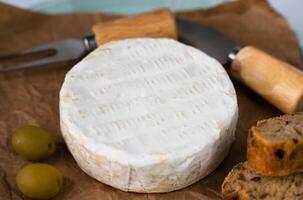 Camembert cheese, olives and sliced fresh baguette on the table. Close-up. Selective focus. photo