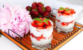 A healthy breakfast dessert with strawberries, yogurt and chia seeds on a wicker tray. Delicious natural and healthy dessert. photo