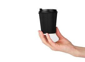 A woman's hand holds a disposable corrugated black paper cup for coffee isolated on a white background. Close-up. Selective focus. photo