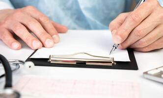 Close-up of a man's doctor's hands filling a form in an office in a hospital. Health and medicine. Selective focus. photo