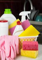 Kitchen detergents, cleaners products and rubber gloves in the basket at the kitchen. Cleaning service concept. Close-up. Selective focus. photo