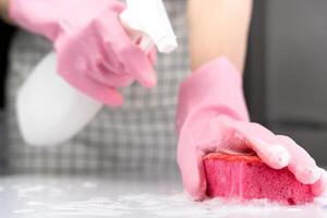 A housewife splashes cleanser onto her sponge. House cleaning concept. Close-up. Selective focus. photo