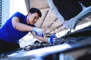 automobile car concept. Asian auto mechanic in blue uniform works on car engine Repair and customer service Working on engines in the garage. photo