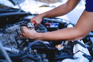 Close-up shot of auto mechanic's hands working on car engine in repair shop. car service technician Work in repair shops and maintenance services photo