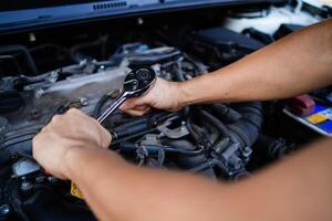 A man is working on a car engine with a socket wrench. Concept of determination and focus as the man carefully works on the engine photo