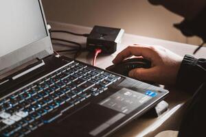 Close up of man's hand using wireless mouse, Raspberry Pi and laptop computer with blue backlit keyboard photo