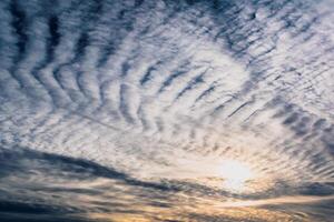 Beautiful striated cloud formation in sky looking like fluffy waves, weather forecast photo