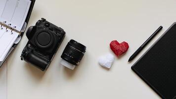 Graphic designer workstation with dslr, lens, agenda, stylus and heart printed in 3d photo