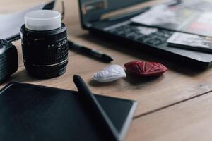 Graphic designer workstation with dslr, lens, laptop, agenda, stylus and 3d objects photo