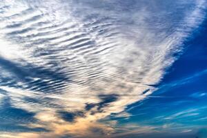 Beautiful striated cloud formation in sky looking like fluffy waves, weather forecast photo