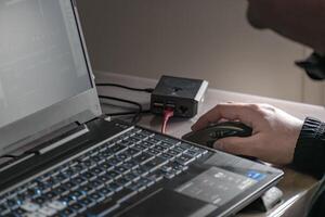 cerca arriba de del hombre mano utilizando inalámbrico ratón y ordenador portátil computadora con azul retroiluminado teclado foto