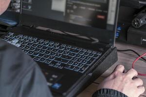 cerca arriba de del hombre mano utilizando inalámbrico ratón y ordenador portátil computadora con azul retroiluminado teclado foto