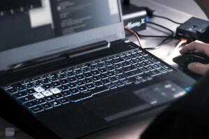 Close up of man's hand using wireless mouse and laptop computer with blue backlit keyboard photo