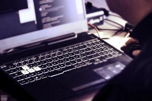 Close up of man's hand using wireless mouse and laptop computer with blue backlit keyboard photo