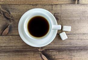 Coffee in a cup and sugar on the table, top view. photo