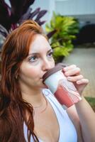 latina mujer Bebiendo un taza de café fuera de en el jardín. foto