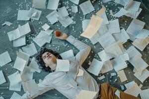 AI generated AI Generated exhausted businessman lying down on the ground with huge of flying documents and paper. photo