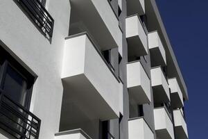 White apartment building against clear blue sky. Isometric photo of balconies