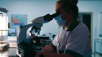 Scientist Researcher examines virus samples under a microscope. Female Research Scientist Looks at Biological Samples Under Microscope. video