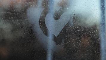 Heart shape on a foggy window against the background of icicles and winter city. video