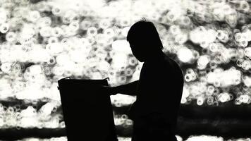 Silhouette of an artist with an easel against the background of an evening river. video