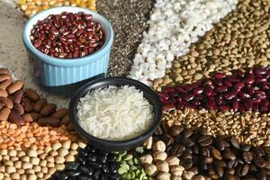 Bowl with raw white rices and beans on various seeds grain photo