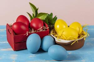 Easter eggs of different colors in a basket and pots with straw photo