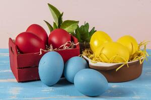 Easter eggs of different colors in a basket and pots with straw photo