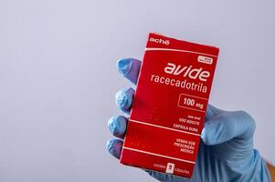 río, Brasil - enero 27, 2023, mano con protector caucho guante participación medicina caja, racecadotril foto