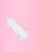 Sanitary pad on pink background. Daily feminine hygiene product. Menstruation concept. photo