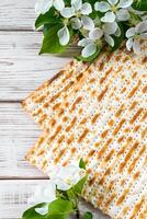 Happy Passover flatlay. Jewish matzo bread and flowers on white wooden background. photo