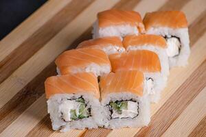 Philadelphia sushi roll on wooden bamboo tray on black background. photo