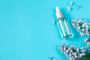 piel cuidado productos cosméticos en azul antecedentes. hidratante suero, crema y delicado lila flores foto