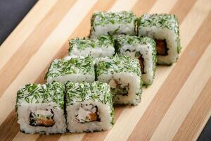 Uramaki sushi roll on wooden bamboo tray on black background. Popular Asian dish. photo