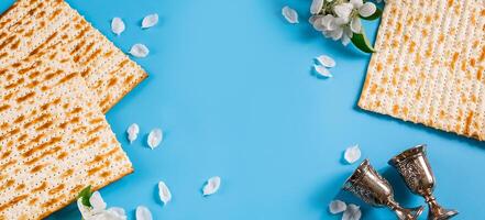 Happy passover flatlay. Metal goblet, spring flowers and traditional matzah photo