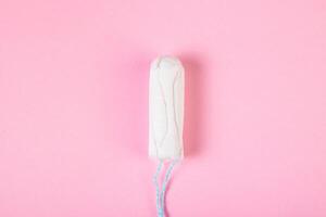 Hygienic cotton tampon on pink background. Feminine menstrual hygiene product. photo