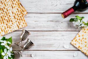judío religioso fiesta de Pascua. botella de vino, matzo y flores en blanco de madera antecedentes. foto