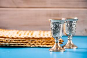 Happy passover. Metal goblet and traditional matzah on blue background. photo