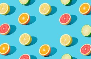 Colorful sunlight fruit pattern made of red grapefruit, orange, lime and lemon slices on light blue background with copy space. Minimal summer concept. Creative food idea. Citrus fruits aesthetic. photo