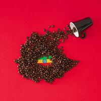 Creative composition made with coffee cup, map of Ethiopia made with roasted coffee beans and Ethiopian flag on red background. Minimal layout. Ethiopia, the home of coffee concept. Flat lay. photo