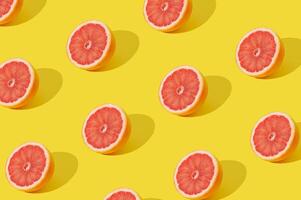 Trendy sunlight fruit pattern made with red grapefruit slice on yellow background. Minimal summer concept. Creative food idea. Grapefruit aesthetic. photo