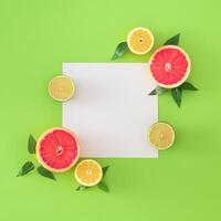 Trendy layout made with grapefruit, lime, lemons, green leaves and paper card note copy space on light green background. Creative food concept. Minimal citrus fruits summer idea. Flat lay. photo